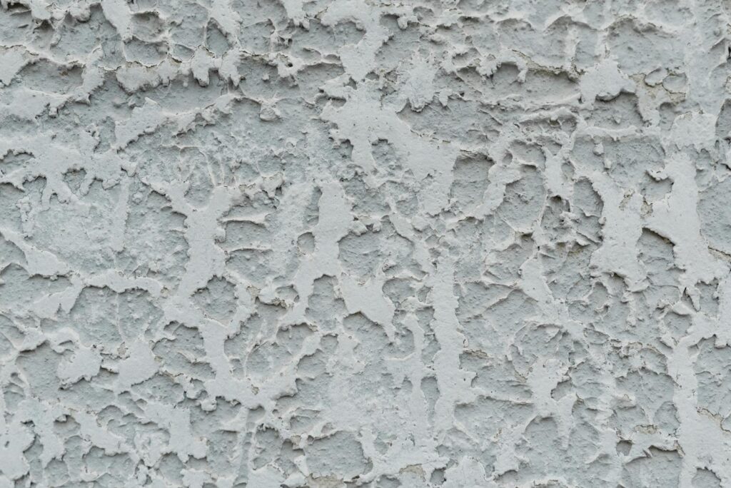 Close-up of a textured stucco wall with weathered, rough patterns and grunge look.